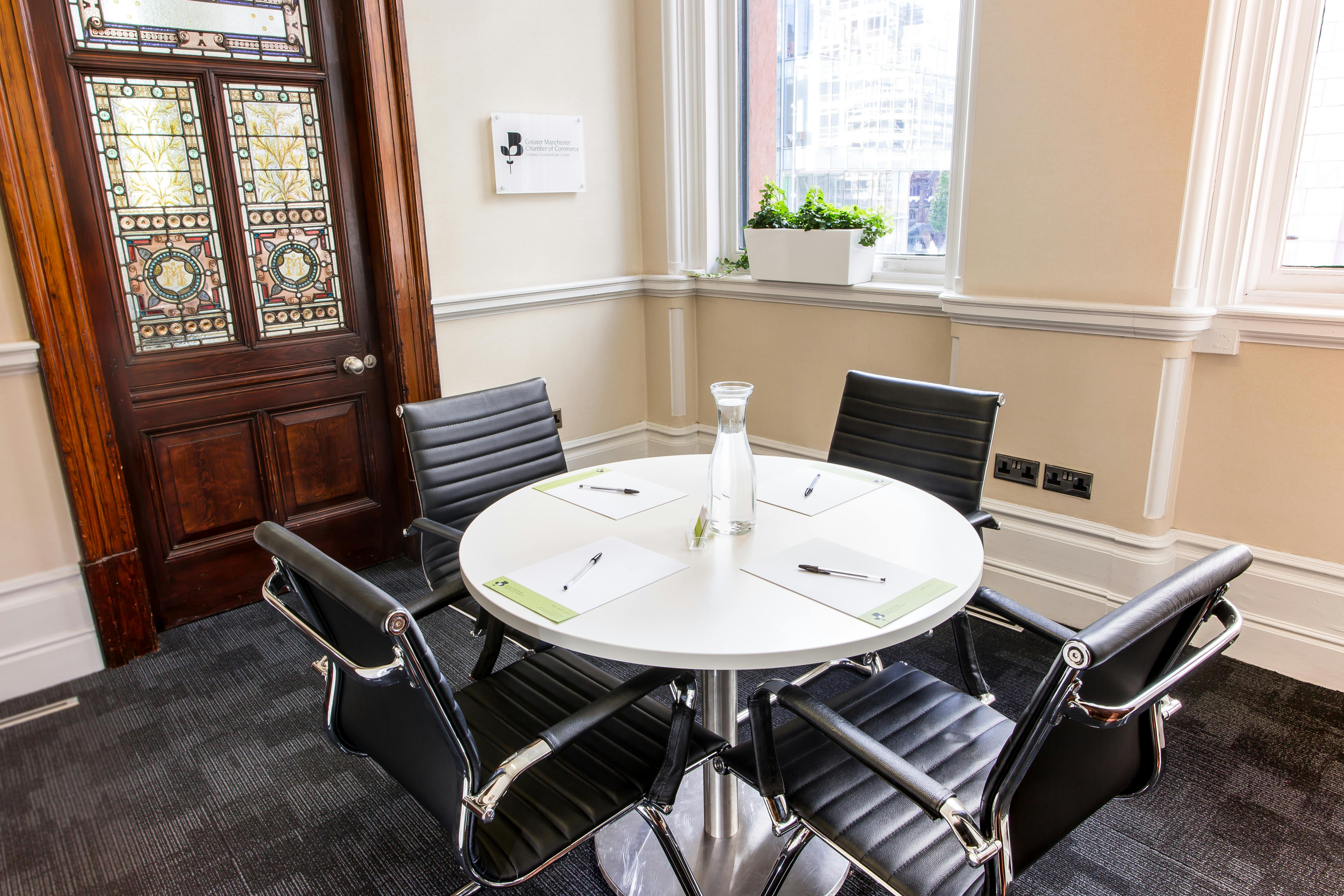 "Modern meeting room with round table, ideal for collaborative discussions and events."