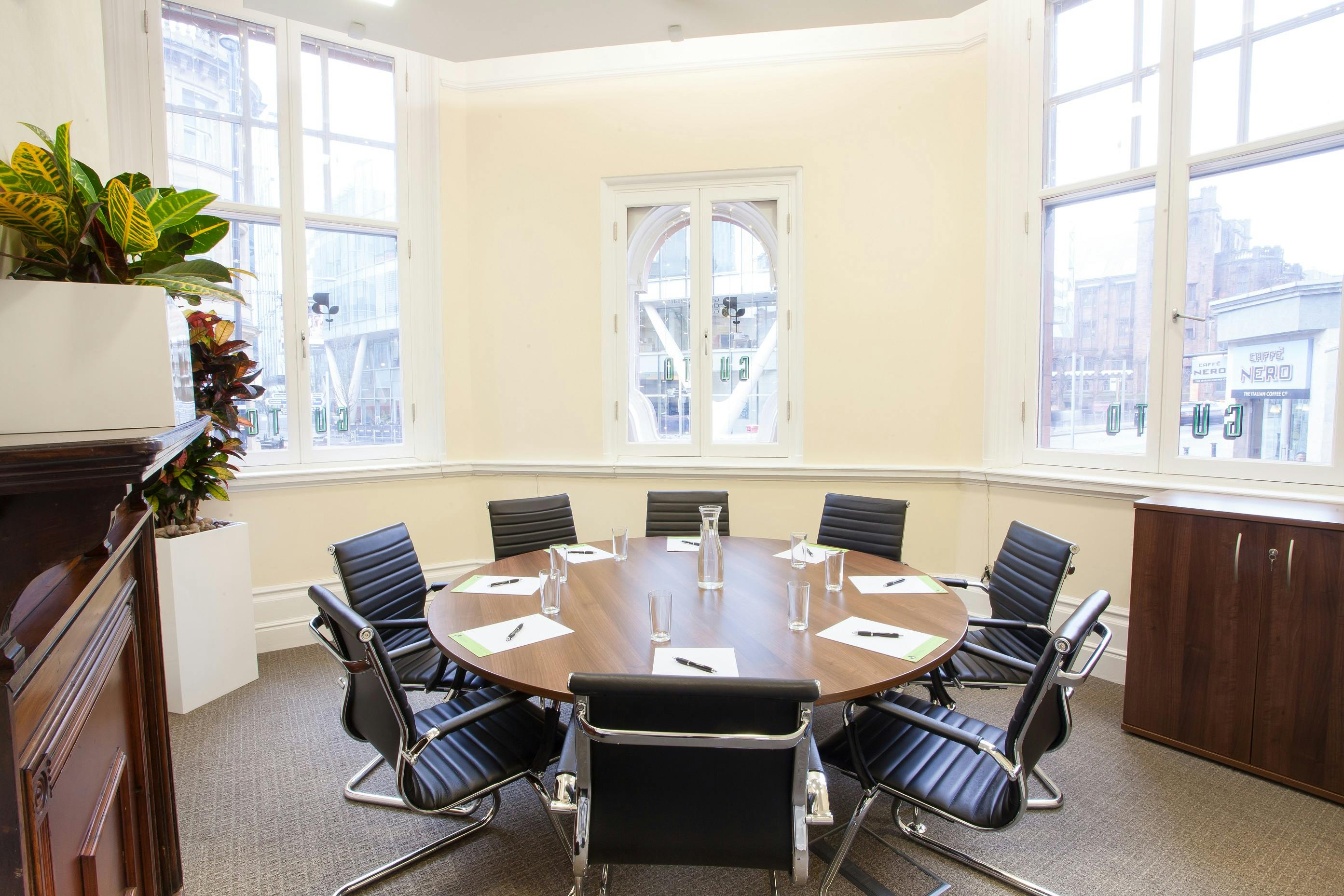 Gusto Room: modern meeting space with round table, ideal for brainstorming and presentations.