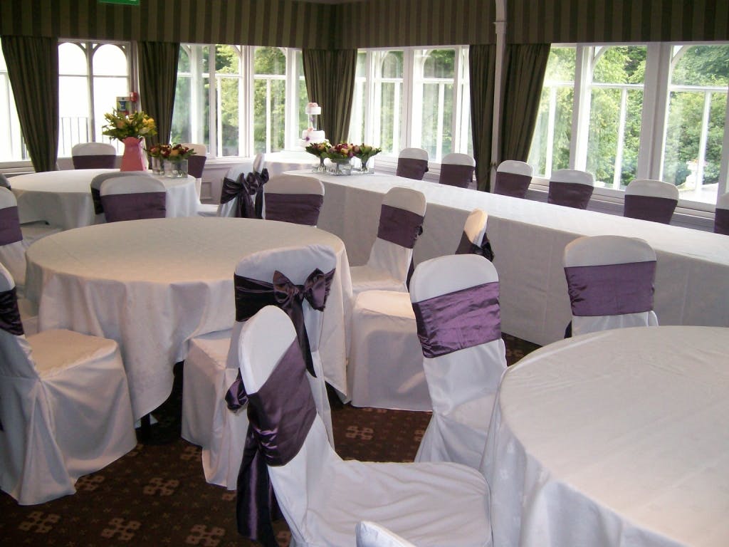 Elegant event space at Norton House Hotel with round tables and purple sashes.