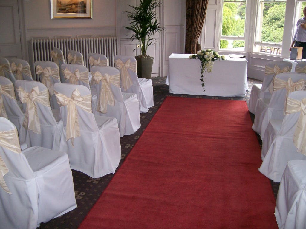 Elegant wedding setup in Norton House Hotel patio with white chair covers and red carpet.