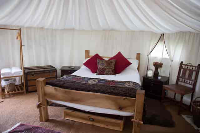 Cozy glamping tent with plush decor for unique outdoor weddings and events.
