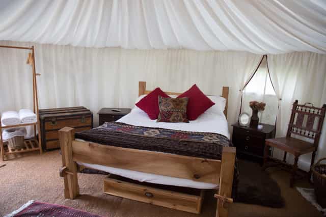 Cozy glamping tent with plush decor for unique outdoor weddings and events.