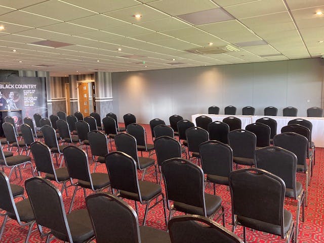 Alan Buckley Lounge at Walsall FC, featuring black chairs for corporate events and presentations.