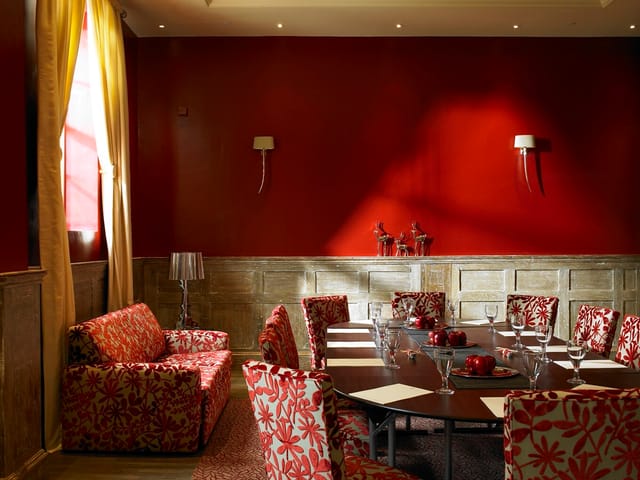 Stylish meeting room with red walls at Fawsley Hall Hotel for events and gatherings.