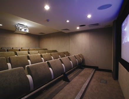 Modern screening room with tiered seating at Grand Jersey Hotel for events and presentations.