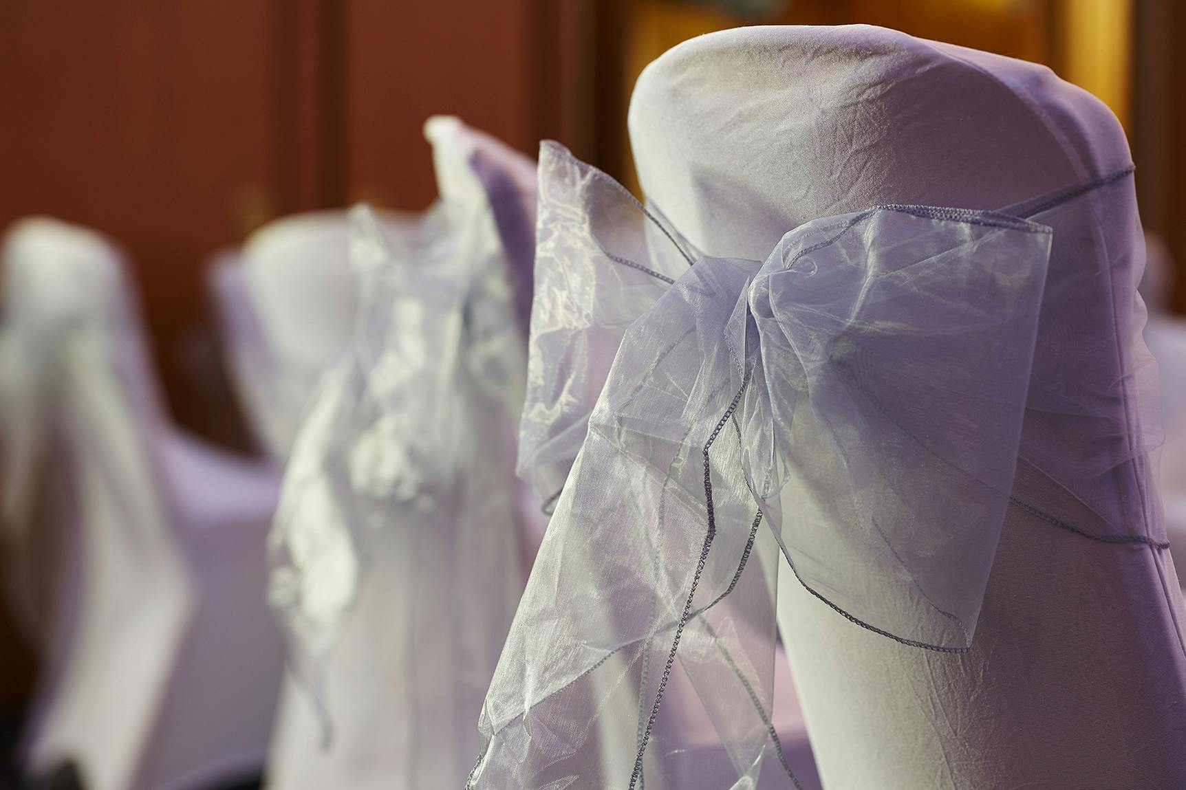 Elegant chair covers with sheer bows in Edward Suite, perfect for weddings and formal events.