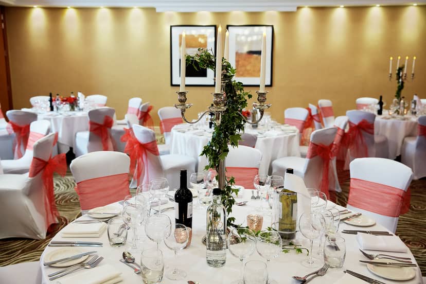 Elegant banquet setup with white linens and pink sashes for weddings and formal events.