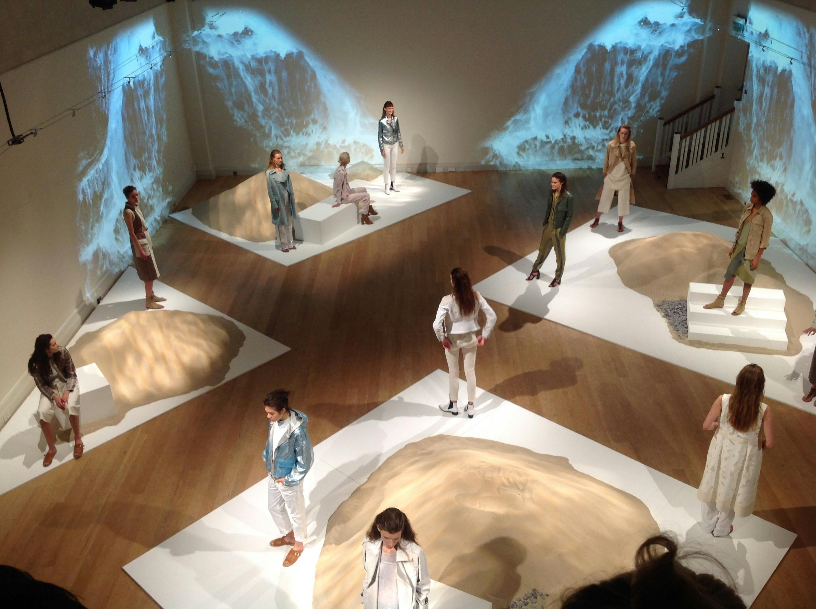 Great Hall fashion presentation with models on sculptural platforms, showcasing creativity.