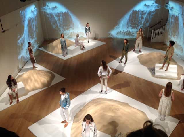 Great Hall fashion presentation with models on sculptural platforms, showcasing creativity.