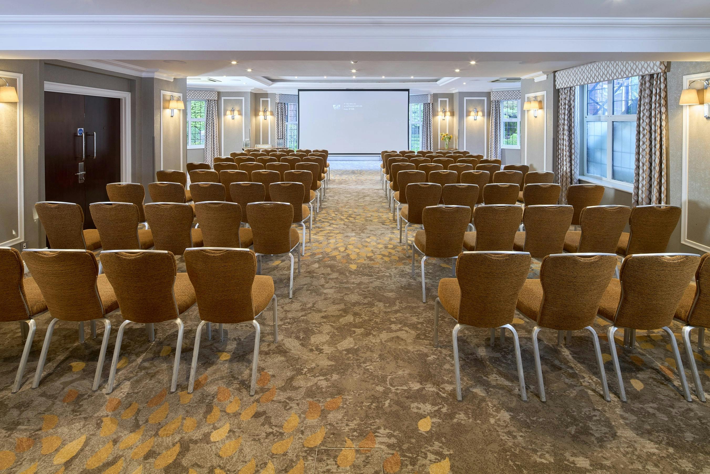 Bulstrode Suite meeting space with chairs and presentation screen, ideal for conferences.