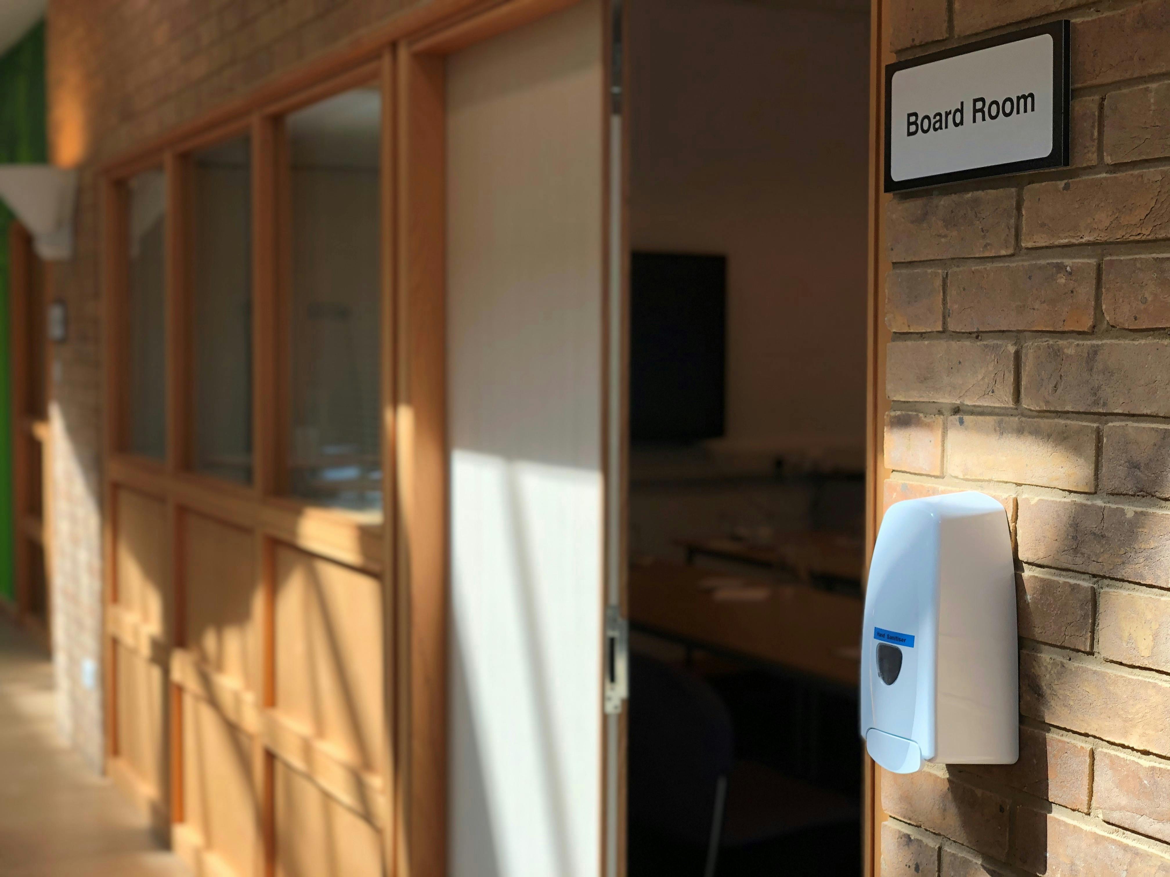 Boardroom entrance with hand sanitizer, promoting hygiene for safe meetings and events.