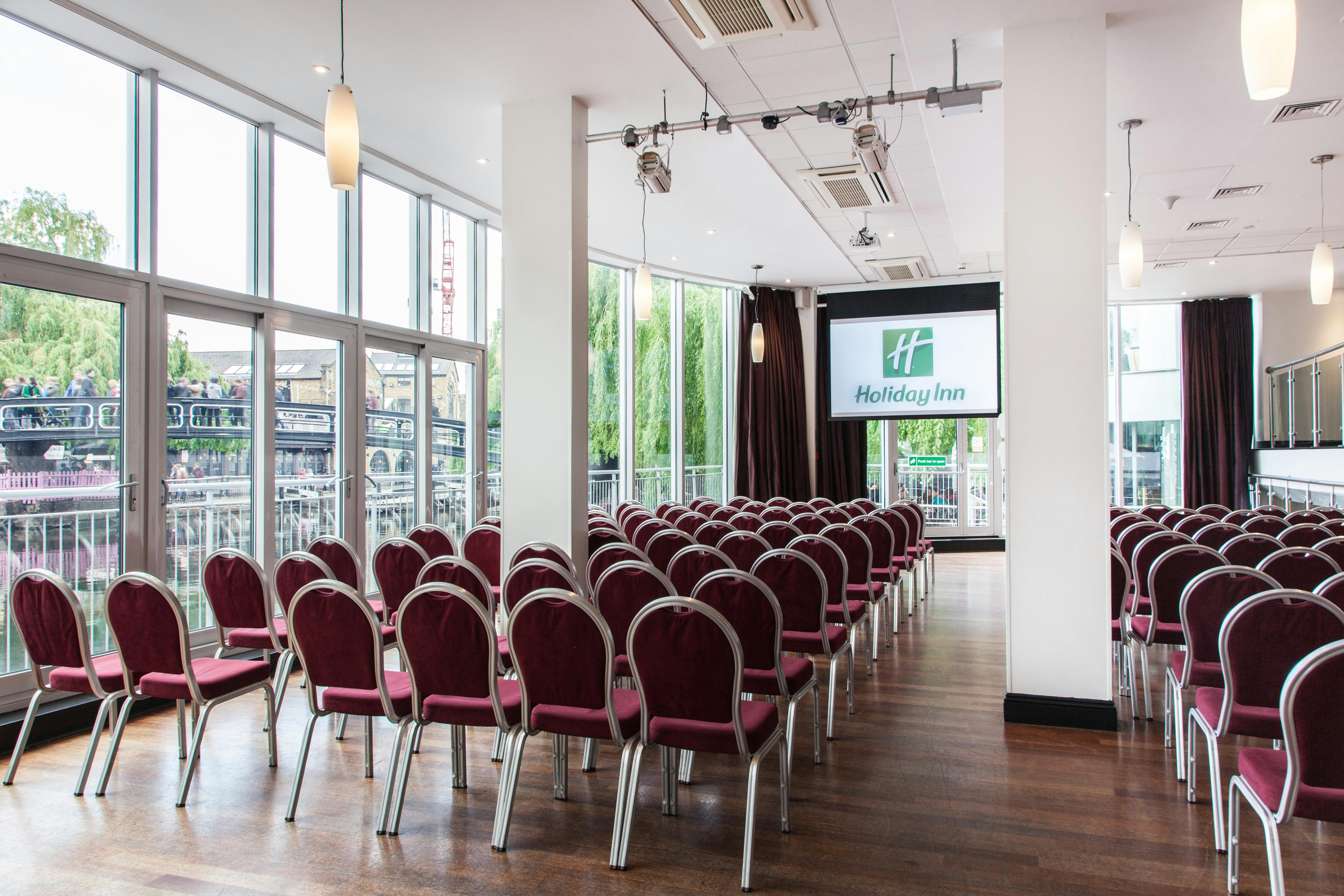 Event space at Holiday Inn Camden Lock with burgundy chairs for conferences and workshops.