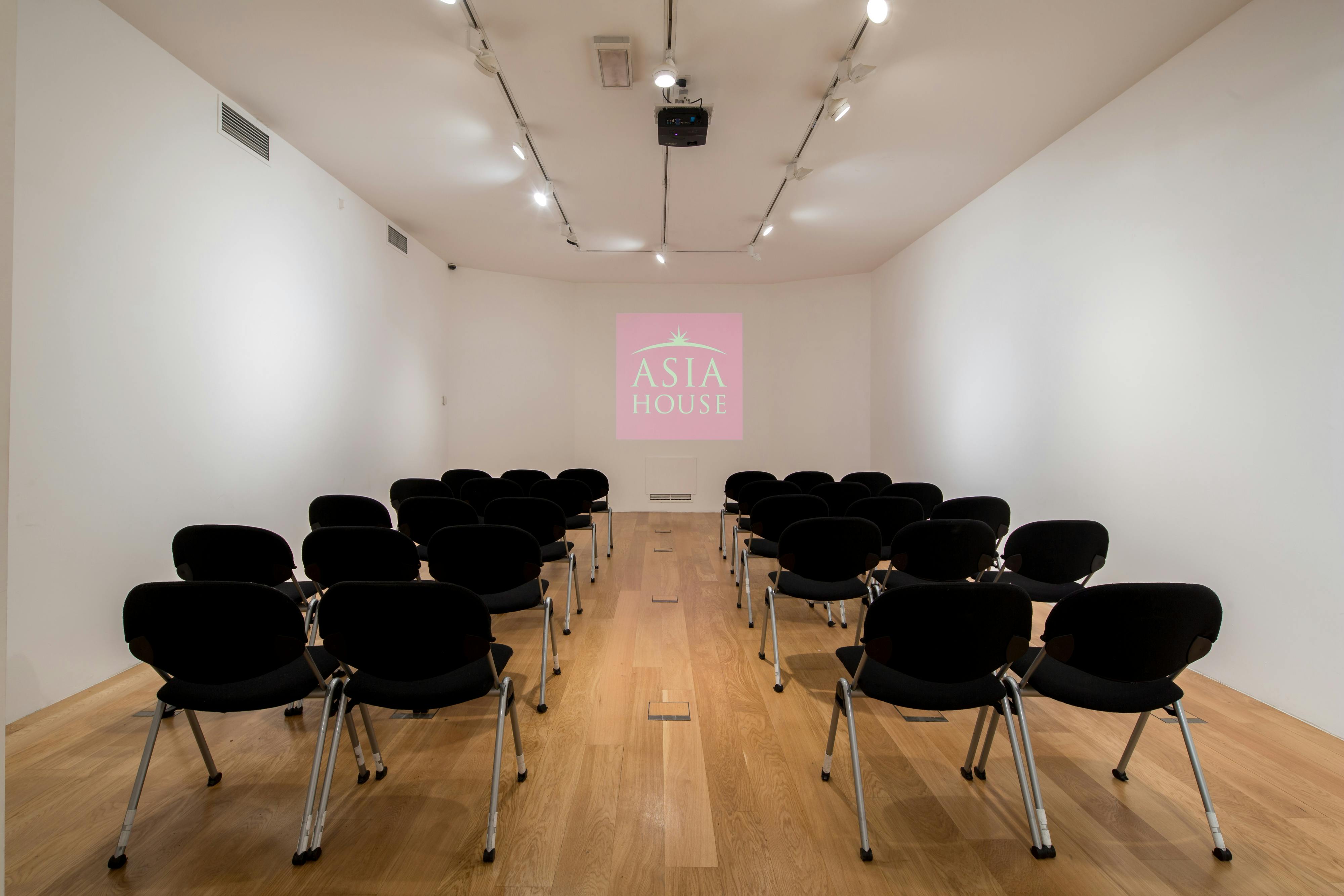 Minimalist event space in Asia House with black chairs for presentations and workshops.
