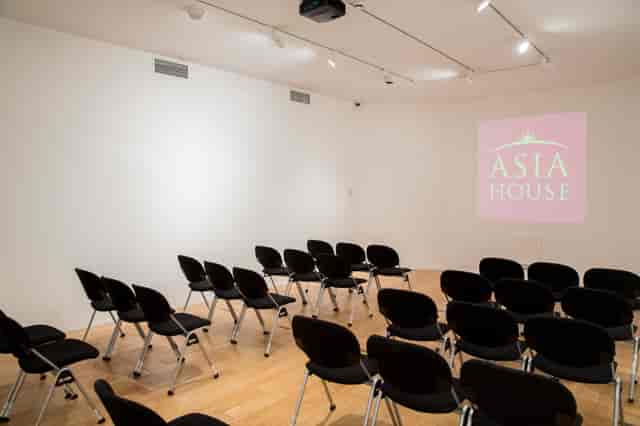 Versatile event space in Asia House set for corporate presentation with black chairs.
