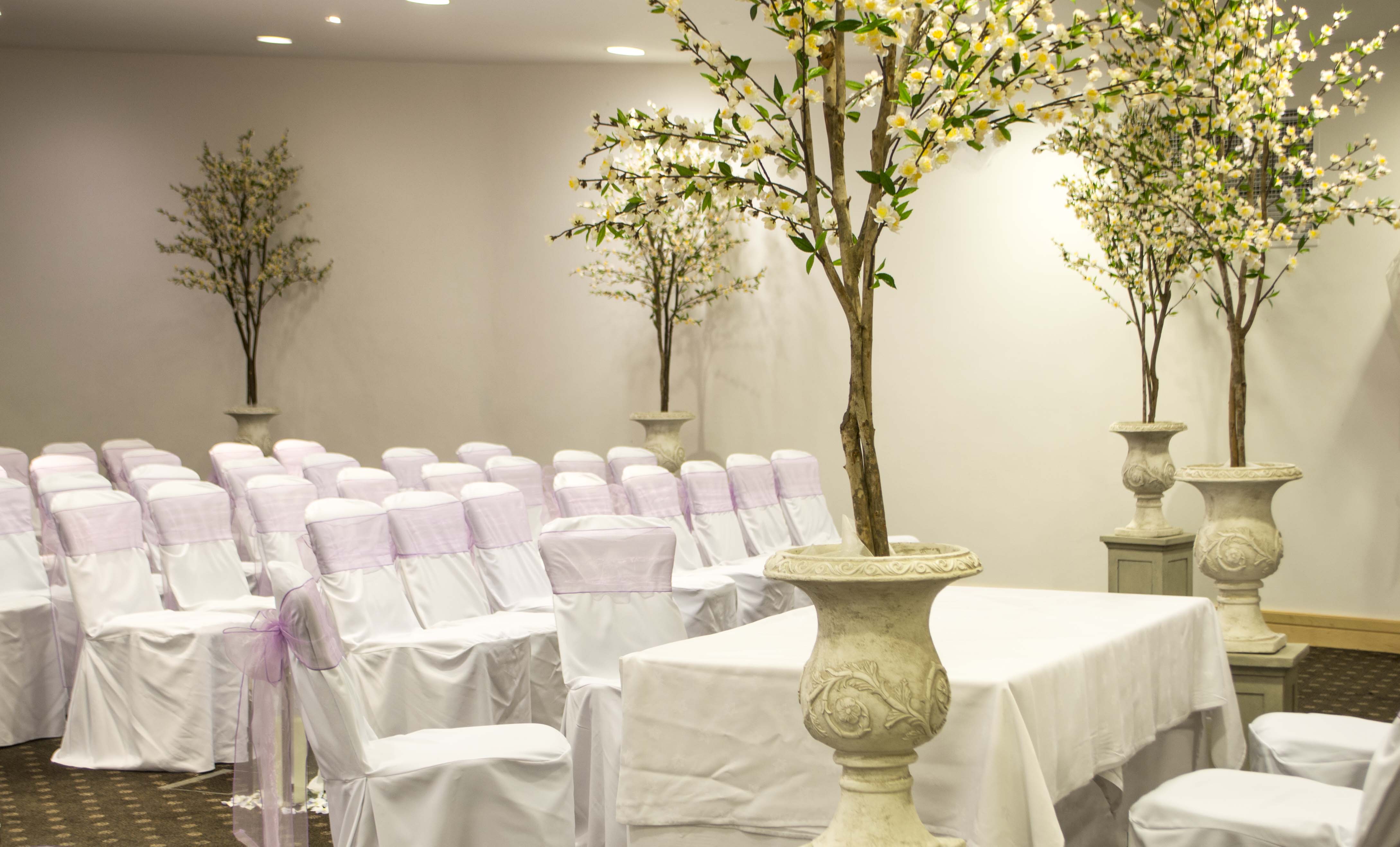 Elegant Beaumont Room with white-covered chairs and lavender sashes for events. - Banner