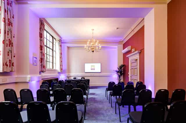 Maurice Barnett in a sophisticated meeting room with black chairs for corporate events.