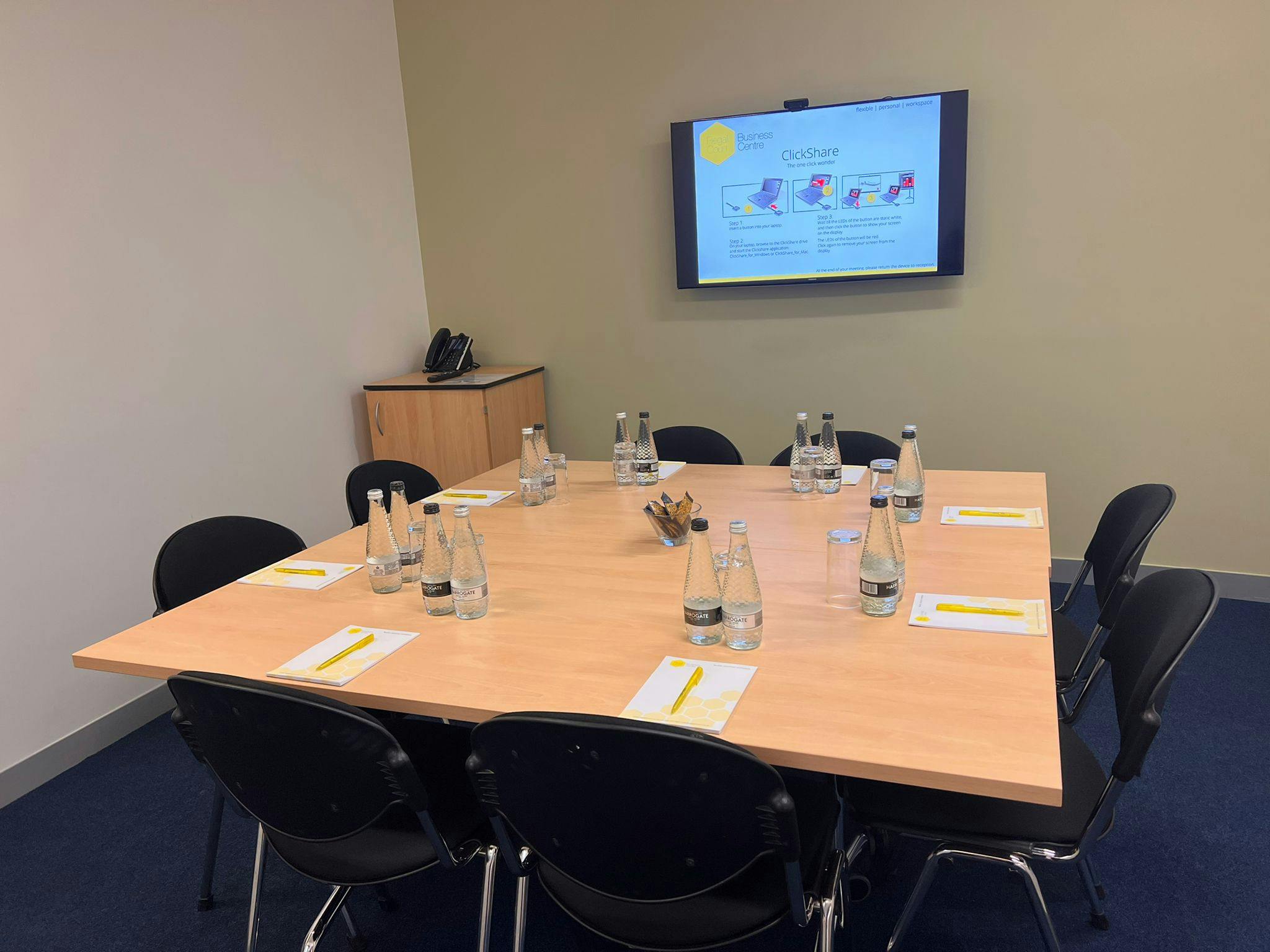 "Meeting room setup with rectangular table, water bottles, ideal for collaborative sessions."