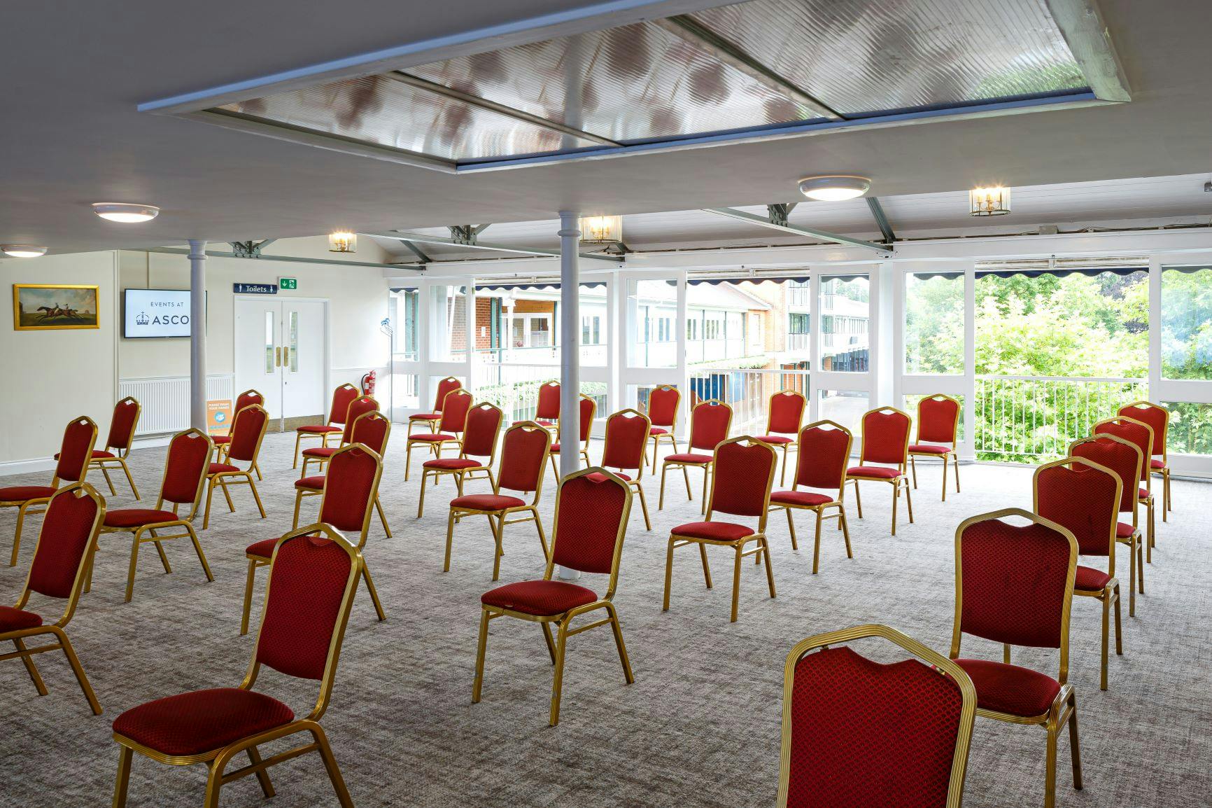 Old Paddock Suite at Ascot Racecourse, spacious meeting space with red and gold chairs.