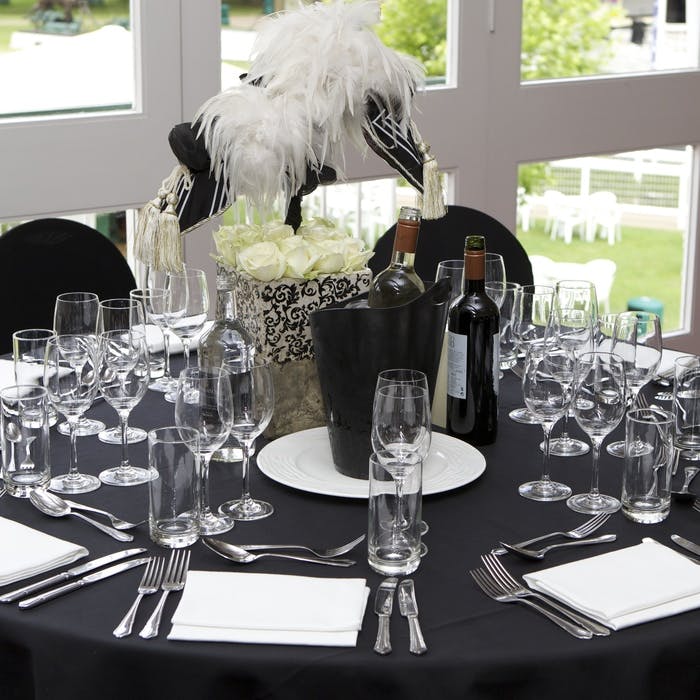 Elegant dining setup with white roses at Ascot Racecourse event.