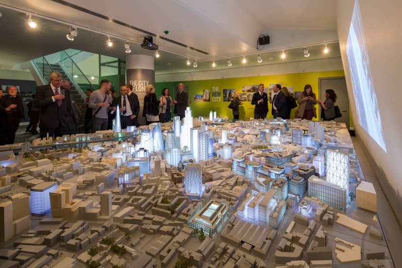 Dynamic event space with illuminated architectural model for urban planning discussions.