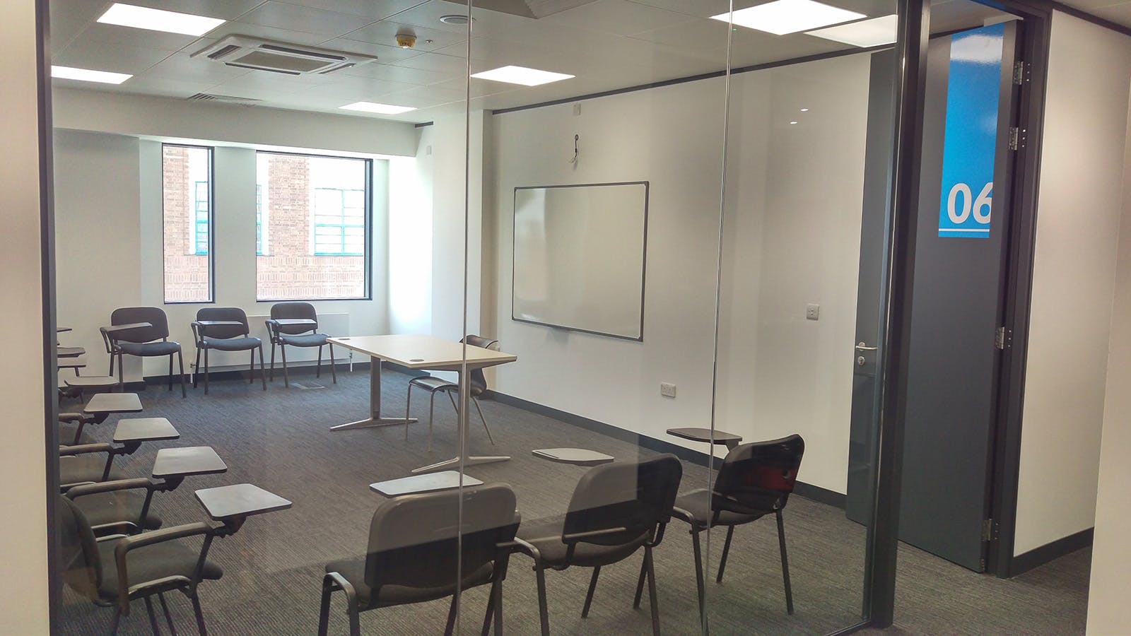 Modern meeting room with glass wall, ideal for workshops and training sessions.