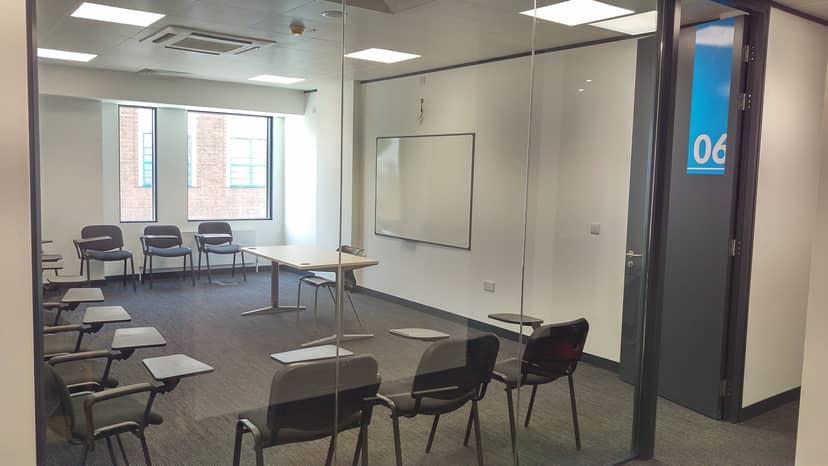 Modern meeting room with glass wall, ideal for workshops and training sessions.