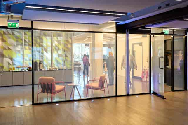 Modern glass breakout space with lounge seating, ideal for corporate networking and conferences.