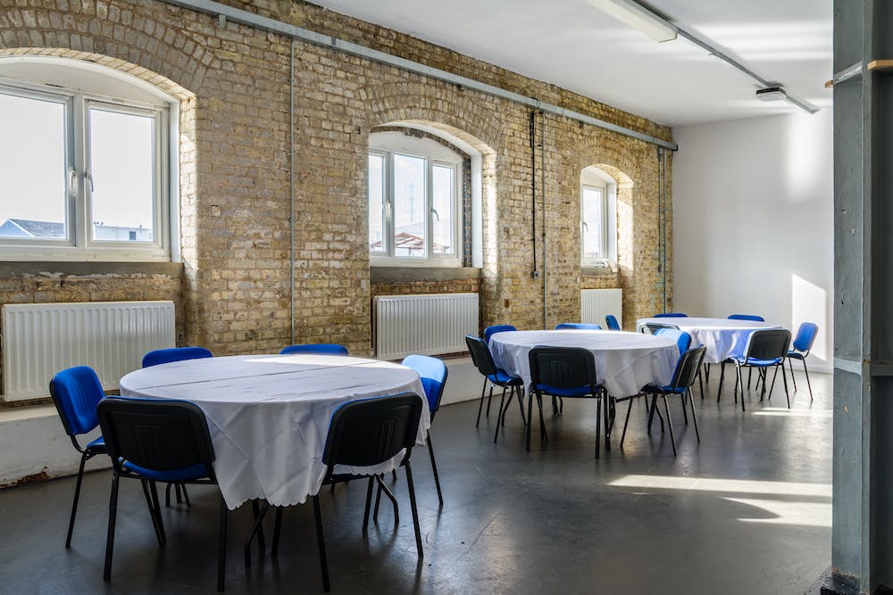 Blue Anchor Studio event space with round tables, ideal for meetings and gatherings.