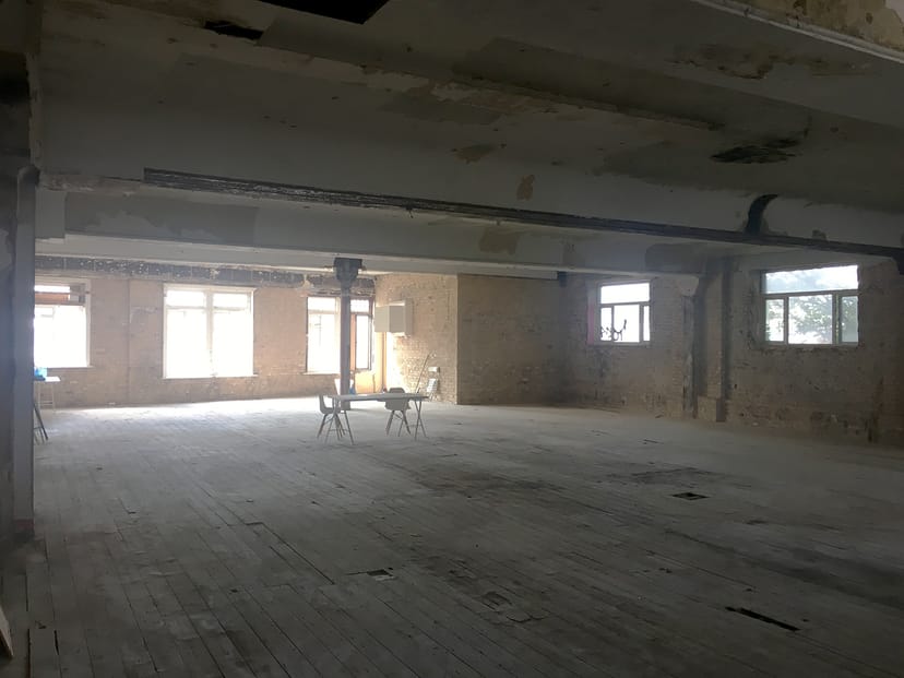 Spacious unfinished event venue with exposed brick and natural light at 133 Rye Lane.