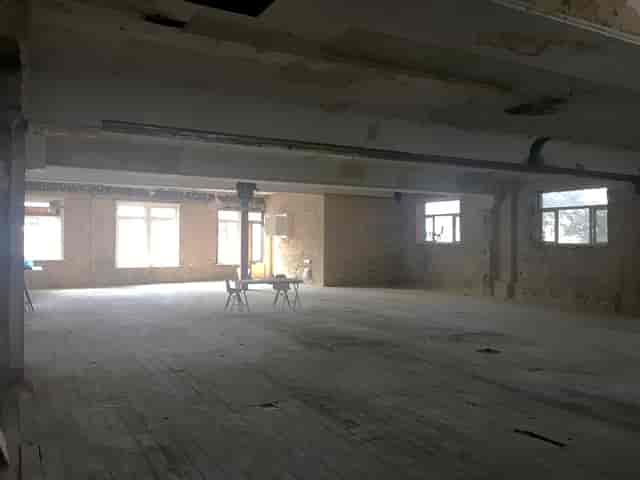 Spacious empty venue with exposed brick walls, ideal for workshops and events.