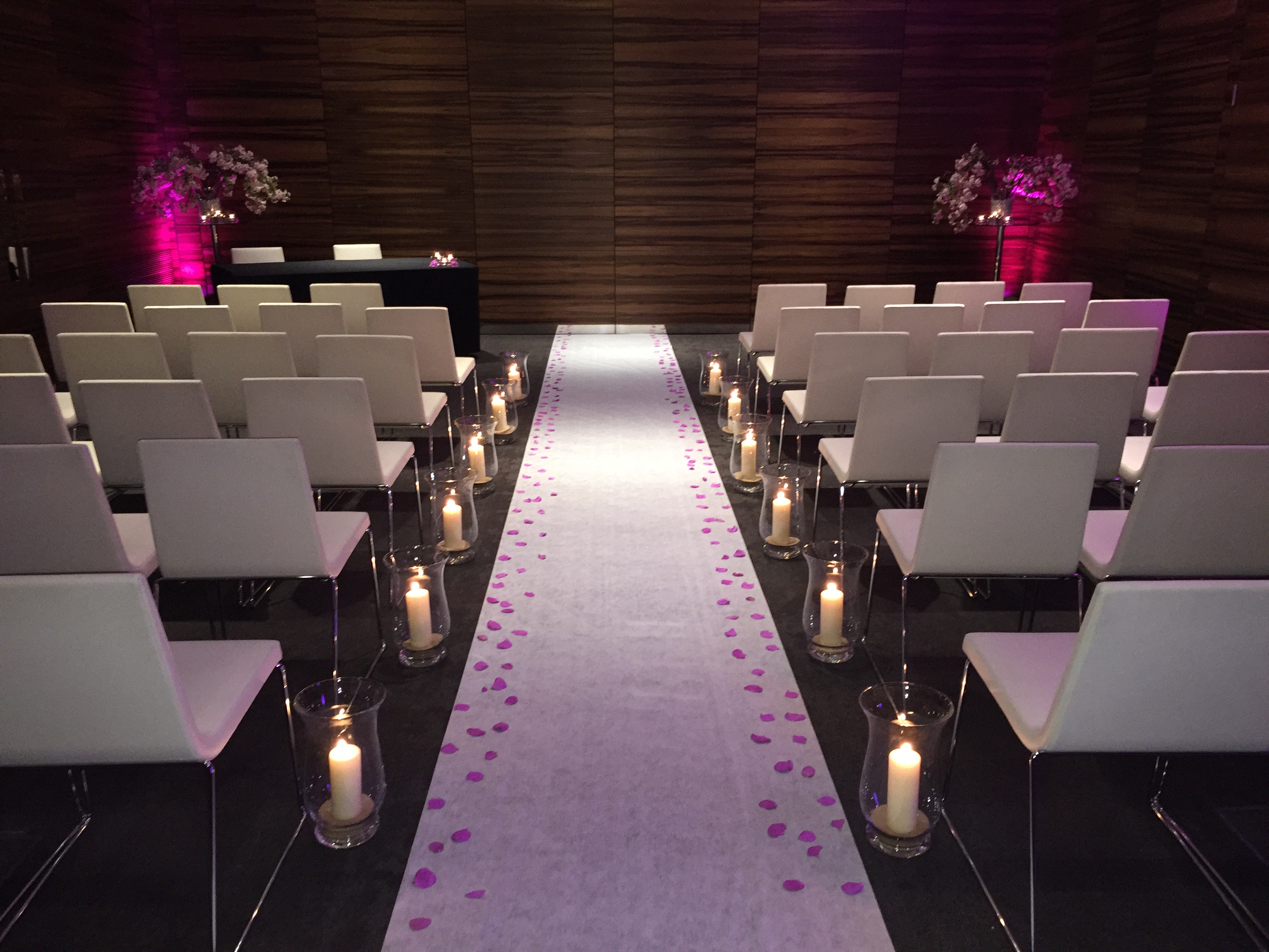 Intimate wedding ceremony space with white chairs and romantic pink lighting in ME London. - Banner
