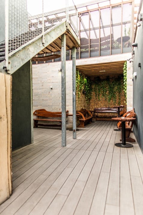 Stylish semi-outdoor meeting space with wooden benches at The Bridge London.