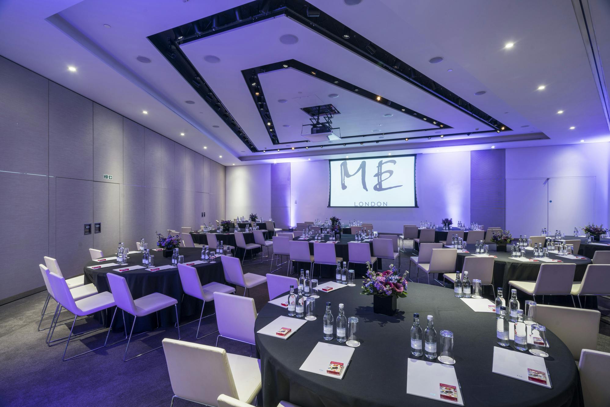 Elegant ME Room in ME London, set for a conference with round tables and ambient lighting.