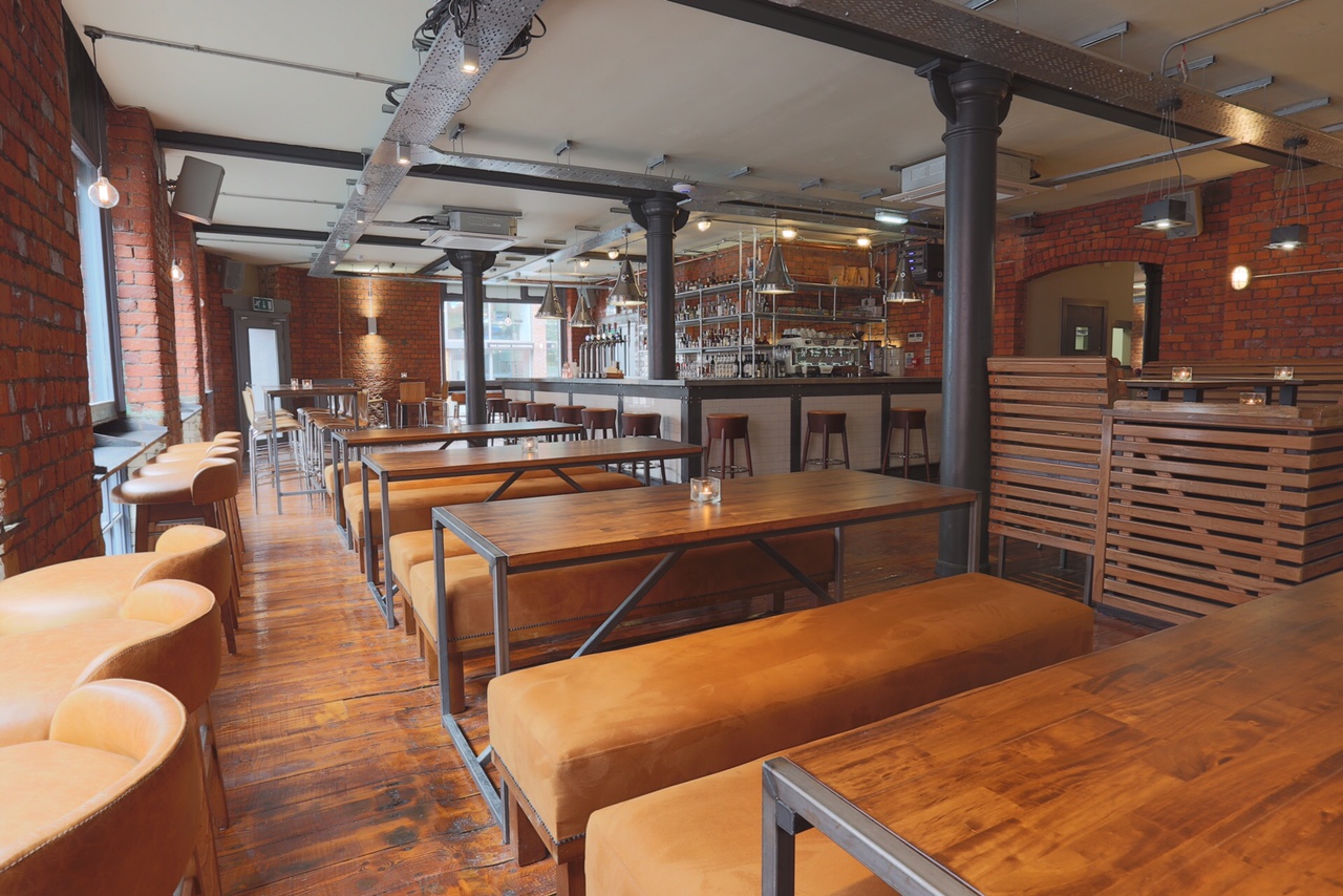 Spacious modern venue with wooden tables, ideal for networking events and casual meetings. - Banner