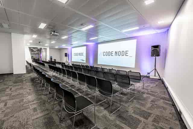 Modern London tech conference venue, tiered seating, screens