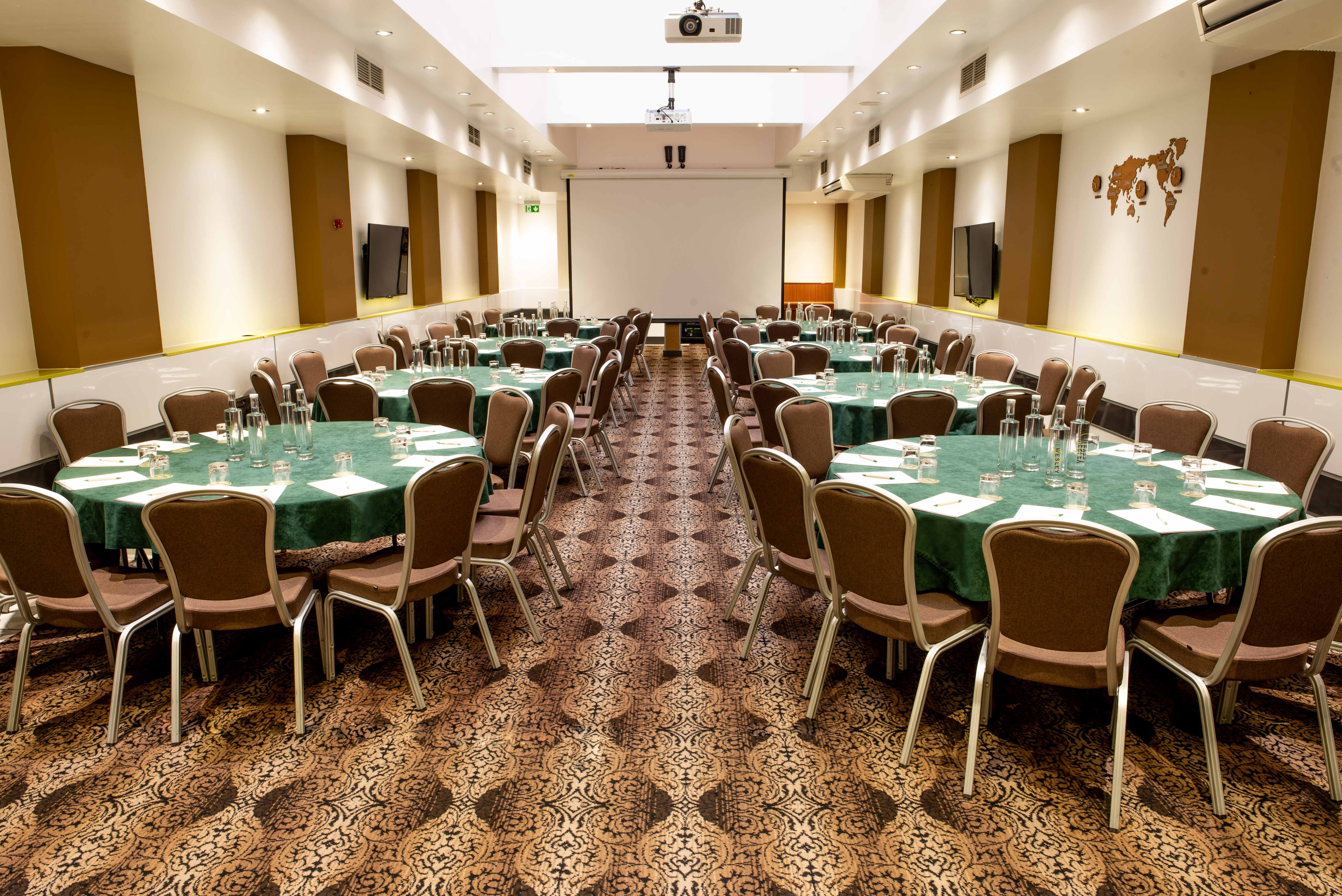 Porter Hall at Wesley Euston Hotel, elegant conference space with green tables and AV setup. - Banner