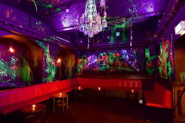 Neon-lit toy room venue with elegant chandelier for themed parties and creative gatherings.