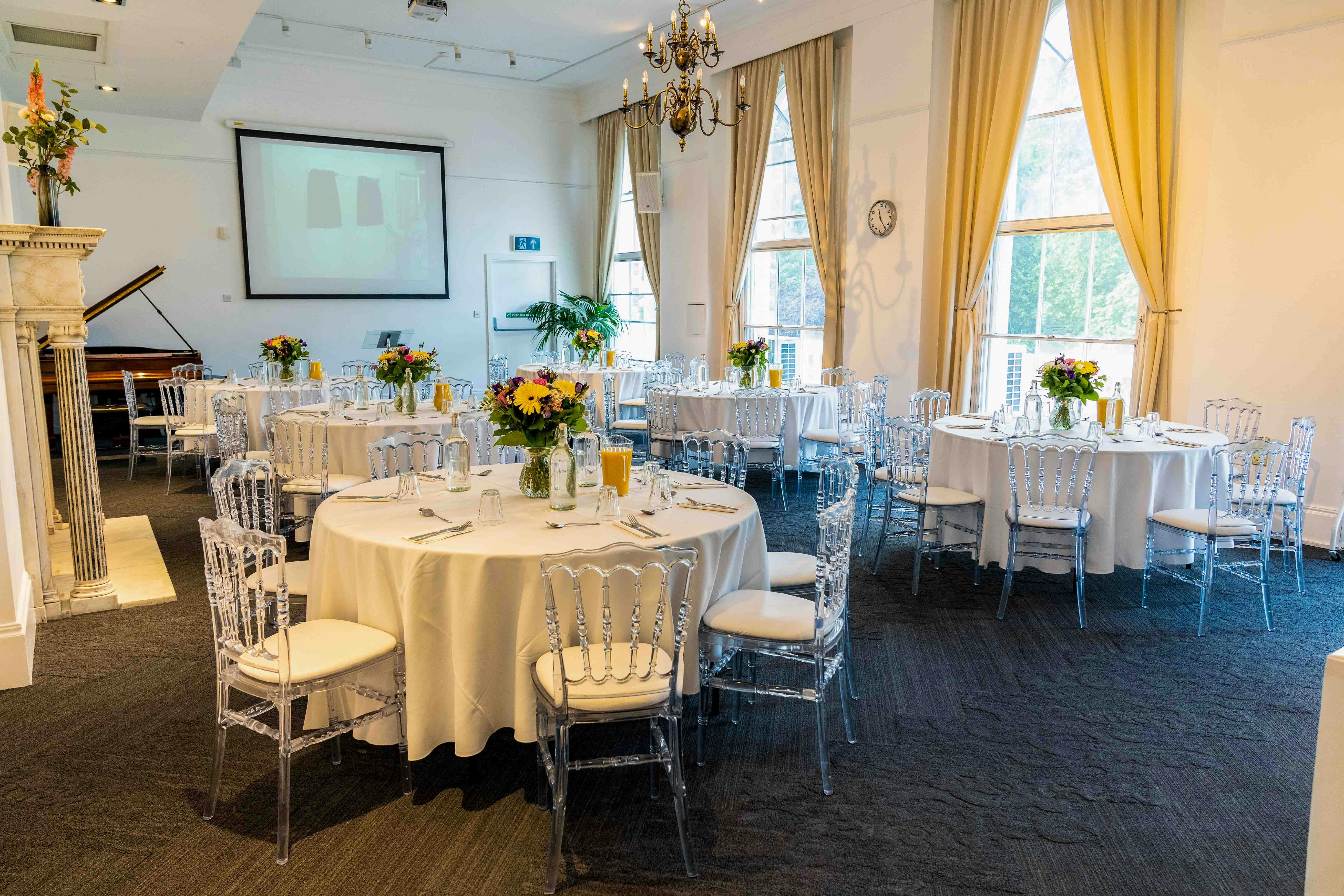 Elegant event space at The Gulbenkian with round tables and projector for meetings.