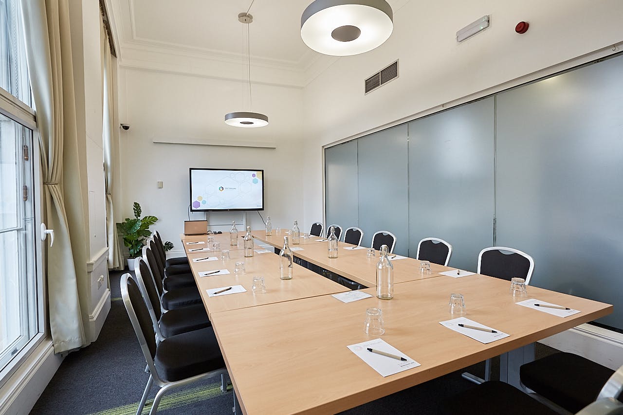 Modern meeting room at The Fitzrovia, featuring a long wooden table for professional events.