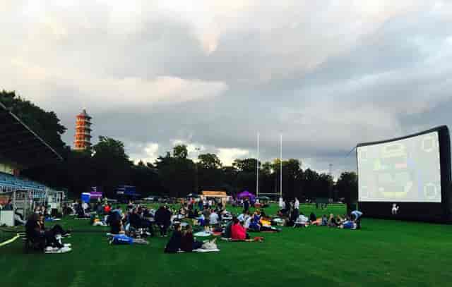 Outdoor event at Dragon's & Lion's Suites with inflatable screen and grass seating.