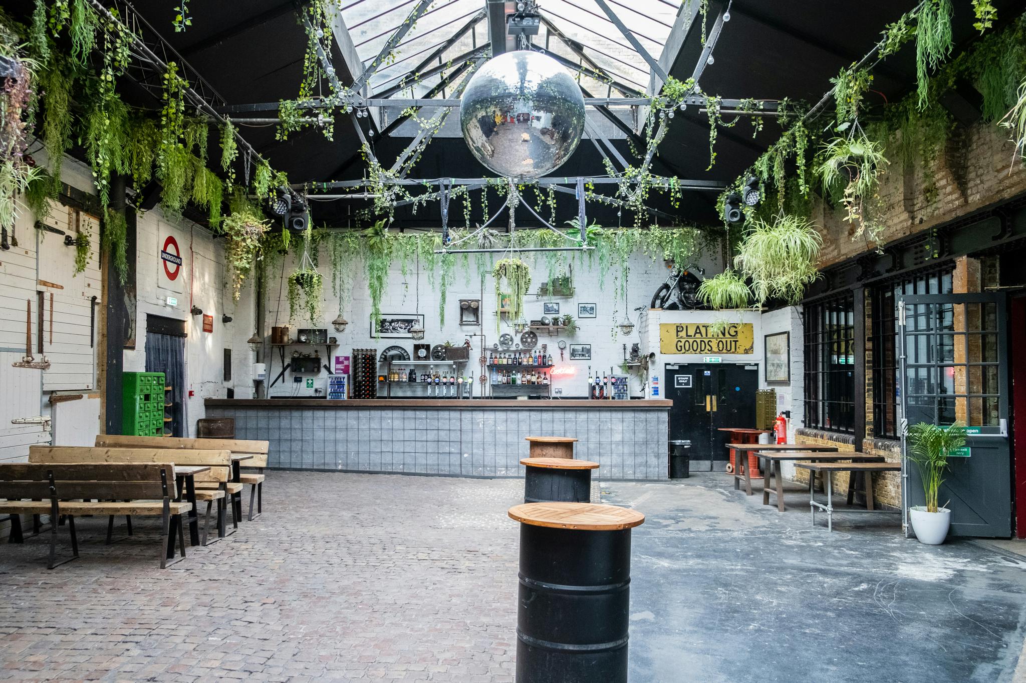 Electrowerkz Courtyard: spacious industrial event space with greenery and central bar.