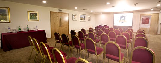 Garden Suite meeting room with burgundy chairs, perfect for presentations and events.