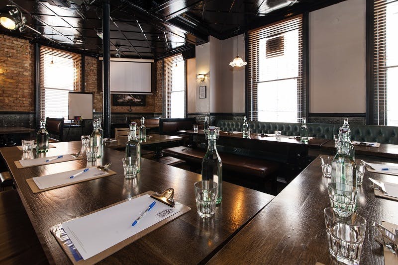 Upstairs Private Bar meeting room with U-shaped tables, ideal for workshops and gatherings.