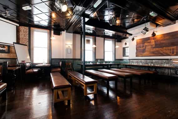 Upstairs Private Bar: versatile event space with wooden benches, ideal for workshops and networking.