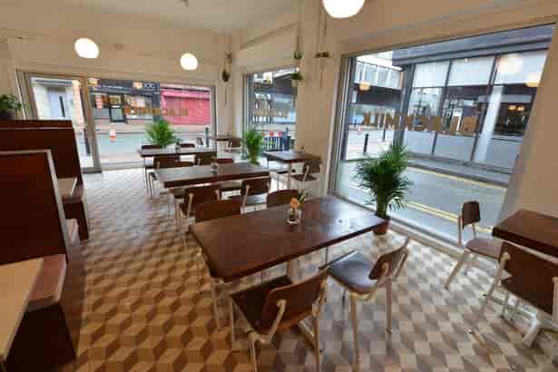 Bright Black Milk Cafe with wooden tables, perfect for casual meetings and networking.