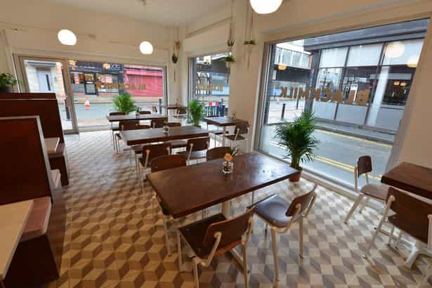 Bright Black Milk Cafe with wooden tables, perfect for casual meetings and networking.
