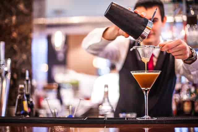 Skilled bartender crafting cocktails at Bella Cosa venue for events and meetings.