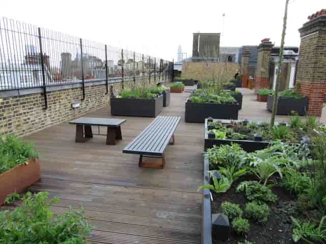 Rooftop garden with wooden decking, ideal for outdoor meetings and events in urban setting.