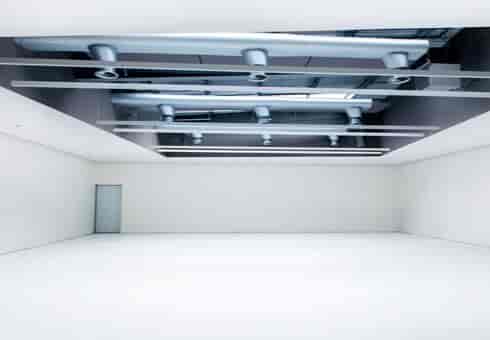 Minimalist event space with high ceiling and natural light for corporate meetings or workshops.
