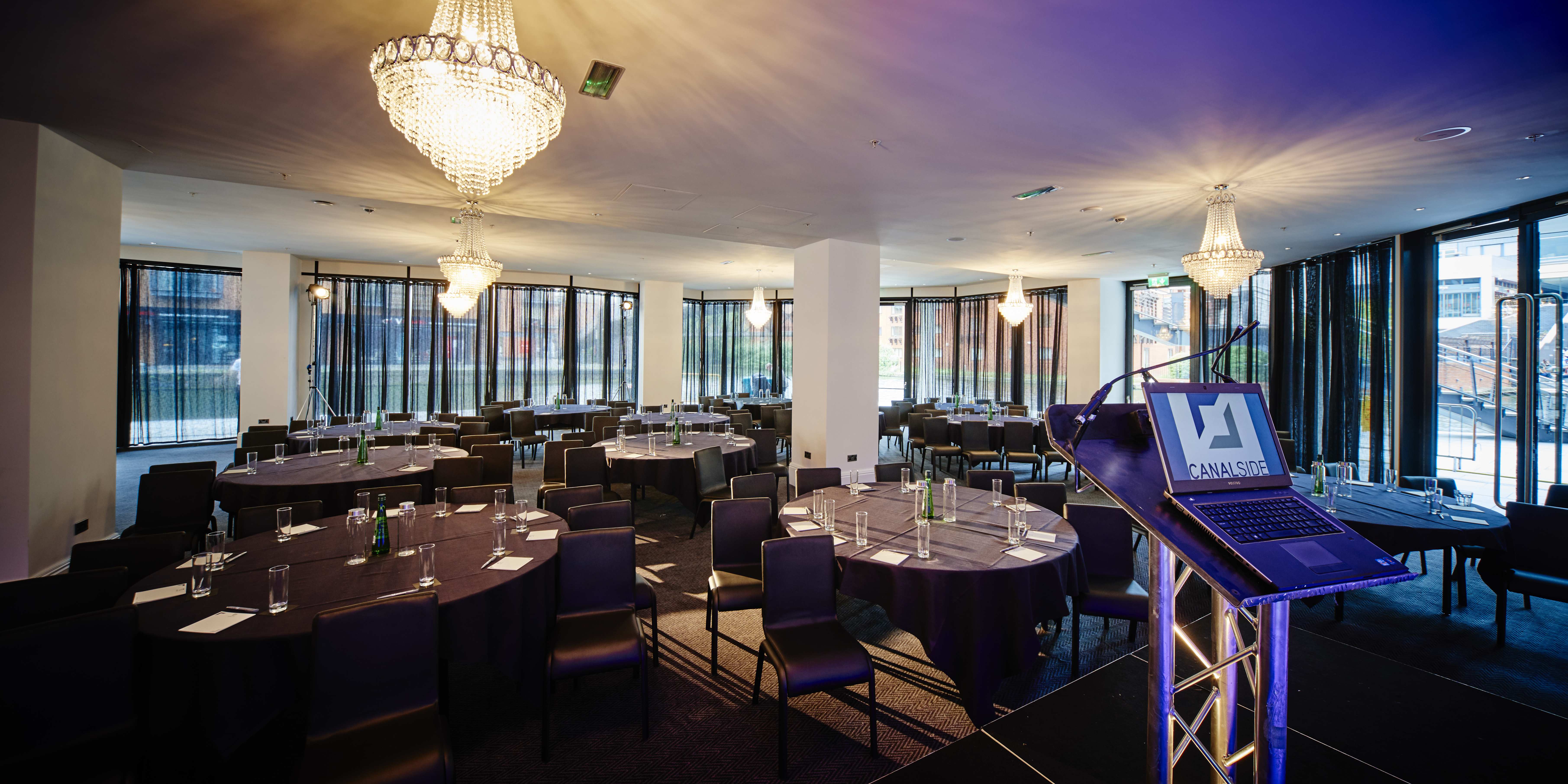 Sophisticated conference venue with round tables and natural light at Canalside. - Banner